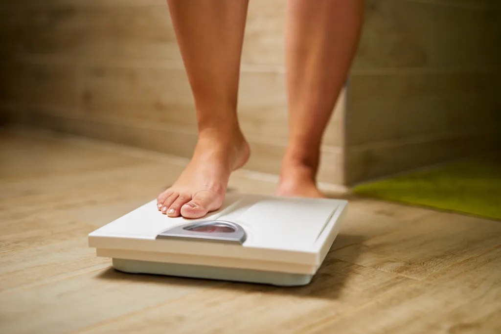 One person's foot is about to step on the weighing scale