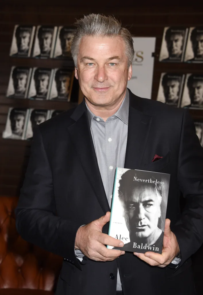 Alec Baldwin holding a magazine.